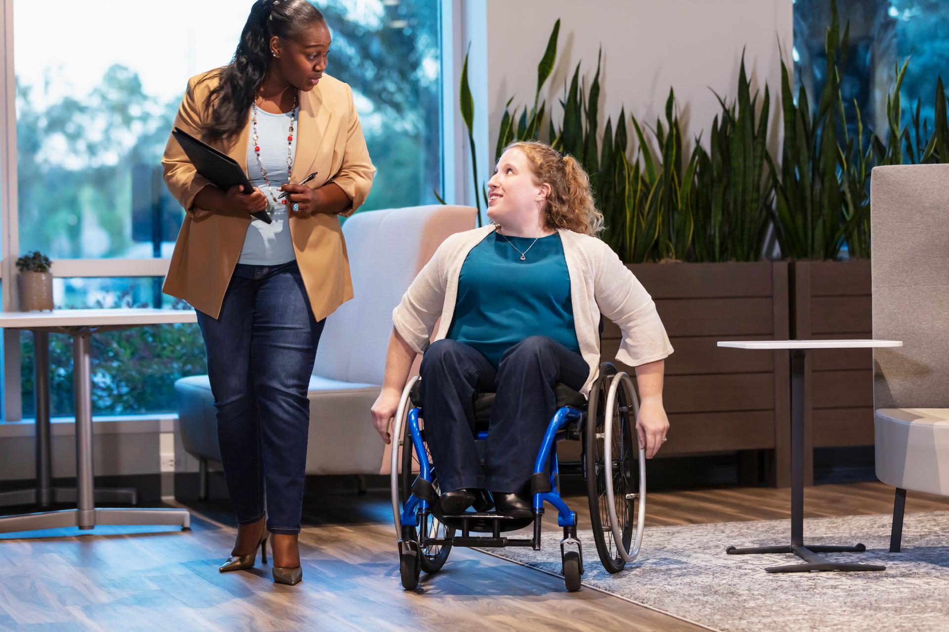 Disabled businesswoman, coworker walking, conversing