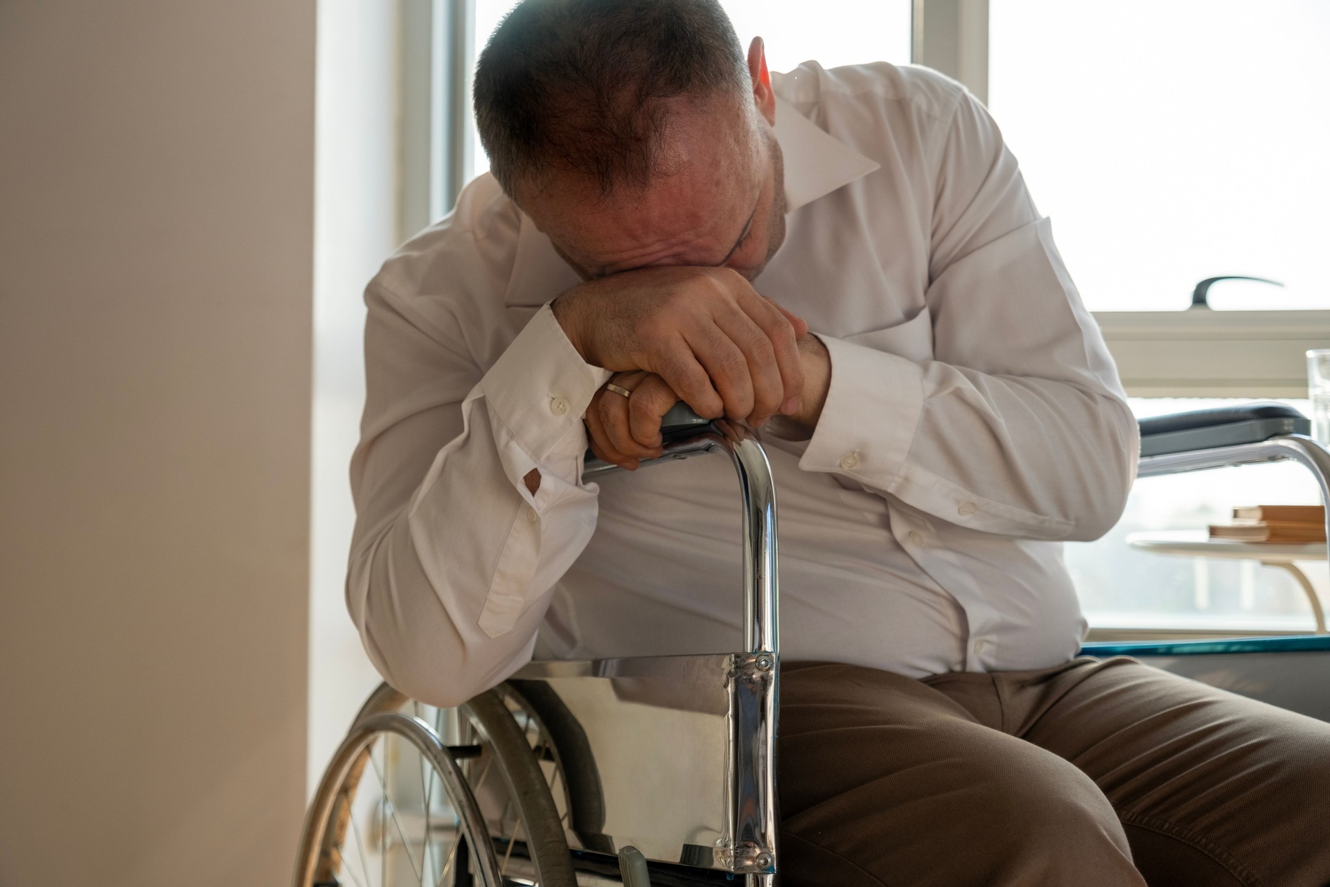A disabled mature man is sleeping in a wheelchair