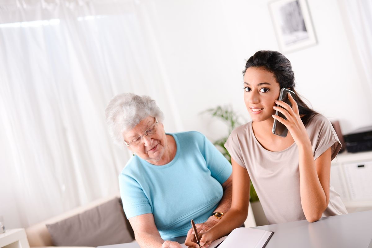 cheerful young woman helping an old person doing paperwork and telephone call